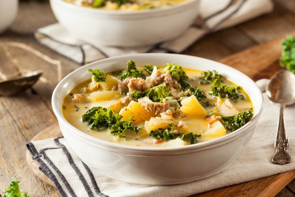 a soup of potatoes beef and some green curly leaves